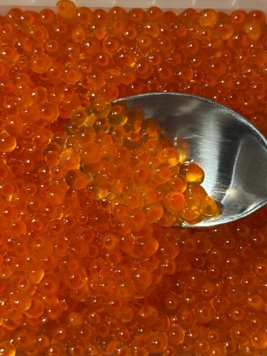 Detaillierte Ansicht von orangefarbenen Fischrohen mit einem Löffel.