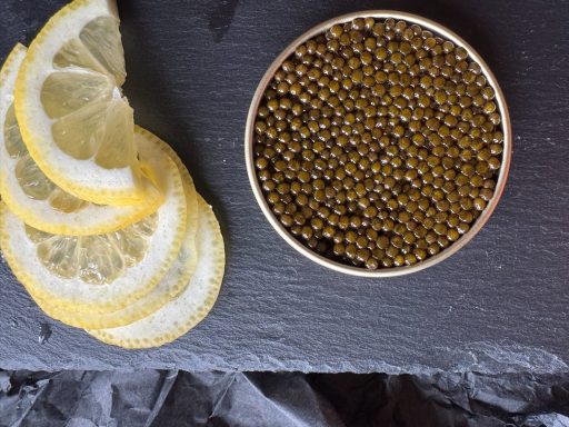 Senfkörner in einer runden Schale neben frischen Zitronenscheiben.